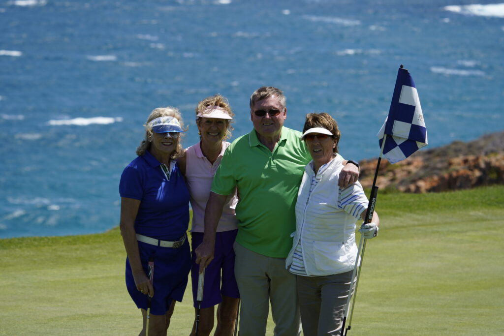 Vier Golfer eines Flights an der Fahne, im Hintergrund das Meer